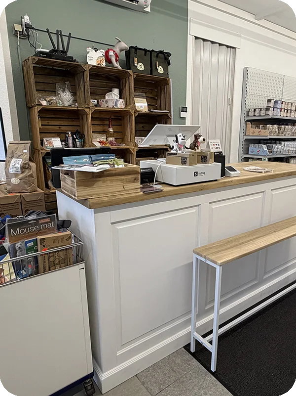 Freundlicher Kassenbereich mit persönlicher Beratung und ausgewählten Tierprodukten im Hintergrund.